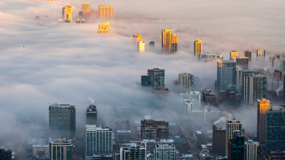 City skyline shrouded in thick smog, showing heavy urban air pollution.